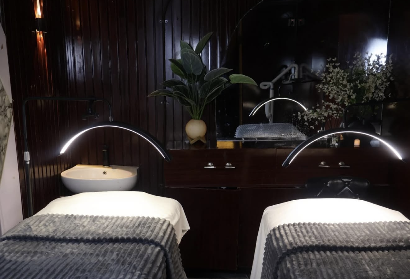 FYRE WELLNESS spa treatment room with twin beds, warm lighting and dark wood walls